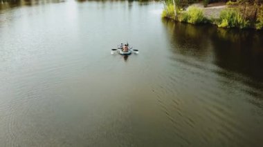 Aerial view of small island with pine trees in the middle of the lake.Unrecognizable people in a boat in the middle of the lake. Close-up shot of island. High quality 4k footage