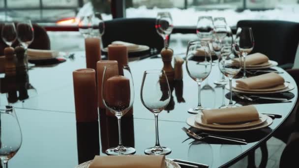 ガラスグラスとホワイトプレート ろうそくはレストランの暗いインテリアで燃えています お祝いのテーブルの装飾 皿は黒いガラスのテーブルの上にある フルHd — ストック動画