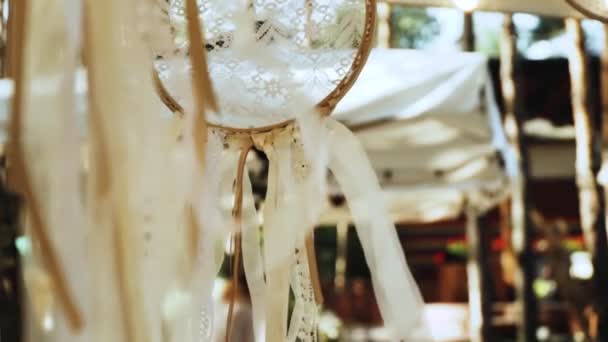 木製の夢のキャッチャークローズアップショットと結婚式の装飾 太陽の光が白い夢のキャッチャーを通して輝き リボンが風に揺れる スローモーションショット 高品質のフルHd映像 — ストック動画