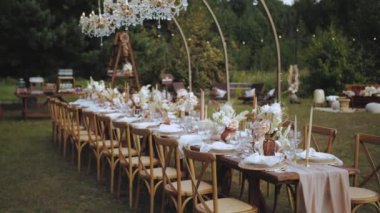Masa, mum ve kurutulmuş pastel çiçeklerle servis edildi. Boho tarzı düğün yemeği, tabaklar ve bardaklar için. Kimse vurulmayacak, yavaş çekim yapılacak. Yüksek kalite 4k görüntü