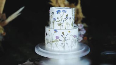 Akşamları kemerin yanında kurumuş çiçeklerle süslenmiş güzel bir düğün pastası, yavaş çekim. Yüksek kalite 4k görüntü