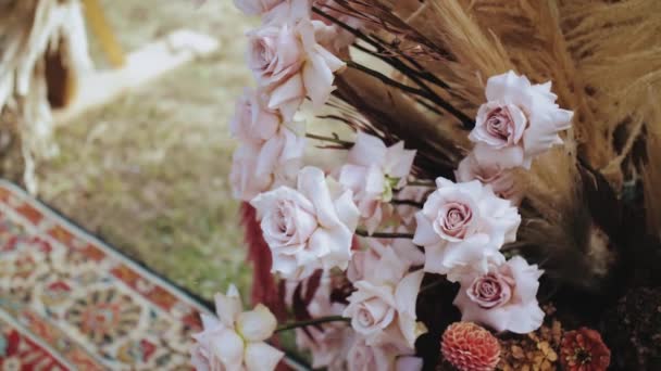 屋外の結婚式で美しいBohoアーチ装飾の一部のクローズアップ パステルカラー ドライフラワー 木製の椅子や昔ながらのカーペットの花の組成物 夏結婚式 — ストック動画