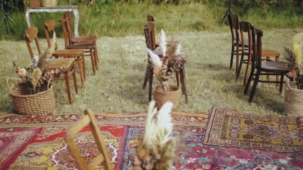 木製の椅子や昔ながらのカーペットのクローズアップ ドライフラワーの花の花の組成 屋外の結婚式で美しい装飾 夏の結婚式スローモーション 高品質4K — ストック動画