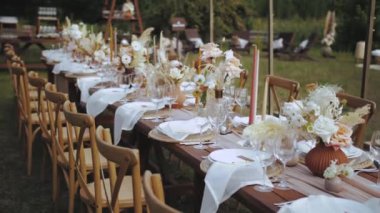 Boho tarzı düğün yemeği, tabak ve şarap bardakları için mum ve kurutulmuş pastel çiçeklerle servis edilmiş ve dekore edilmiş bir masa. Yüksek kalite 4k görüntü