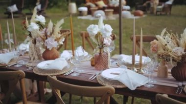 Kapalı masa, mum ve kurutulmuş pastel çiçeklerle servis edilir. Boho tarzı düğün yemeği, tabaklar ve bardaklar için. Kimse vurulmayacak, yavaş çekim yapılacak. Yüksek kalite 4k görüntü