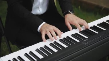 Piyano çalan adam. Açık hava partisinde elektrikli piyano çalan genç adamın elleri. Müzik aleti çalıyor, ağır çekim. Yüksek kalite 4k görüntü