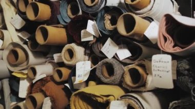 Kumaş ve tekstil ruloları mağazadaki raflara istiflenmiş. Depo çeşitli kumaşlar, yavaş çekim. Yüksek kalite 4k görüntü