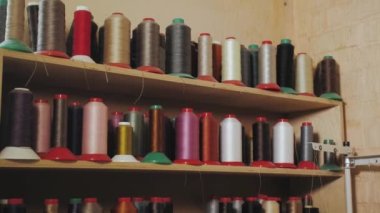 The camera moves from on assorted spools of thread on shelves in shoemaker workshop, slow motion. High quality 4k footage