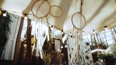 Düş kapanı ile düğün süslemesi. Güneş ışınları, rüzgarda sallanan kurdelelerle beyaz renkli düş kapanı boyunca parıldıyor. Yavaş çekim. Yüksek kaliteli FullHD görüntüler