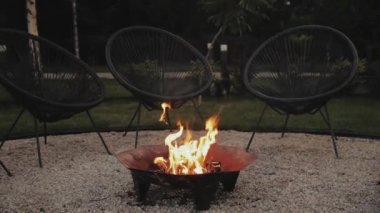 Arka bahçede sıcacık bir şömine. Sakin bir yaz akşamı ve sıcak bir ateş, ağır çekim. Yüksek kalite 4k görüntü