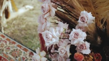 Güzel bir düğün çiçeği süsü. Düğün kemeri, pastel pembe güller ve otlarla düzenlenmiş, kamera ağır çekimde hareket ediyor. Yüksek kalite 4k görüntü