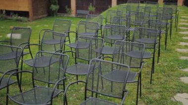 Close-up of black empty chairs at the wedding ceremony in a park, green lawn on the background, slow motion. High quality 4k footage