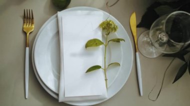 Top view of beautiful wedding decor, all decorated in white, green colors style. Classic served plates and golden forks on the table. camera moving slow motion. . High quality 4k footage