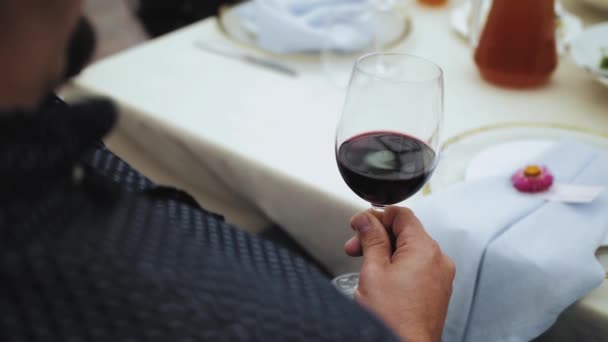Eine Männerhand Hält Bei Der Hochzeit Einen Glaskelch Mit Rotwein — Stockvideo