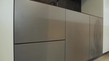 Modern lüks gri ve siyah mutfak iç mimarisi. Gri metal cepheli şık bir mutfak, siyah tezgah ve siyah bir musluk, dolly shot, yavaş çekim. Yüksek kalite 4k görüntü