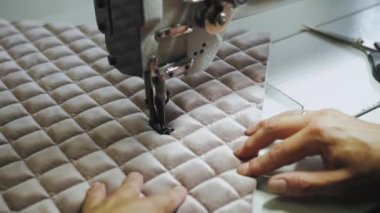 Womans hands sewing fabric on the automatic sewing machine. Close-up seamstress sews elements for furniture. High quality 4k footage