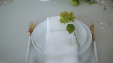 Top view of beautiful wedding decor close-up, all decorated in white, green colors style. Classic served plates and golden forks on the table. camera moving slow motion. . High quality 4k footage