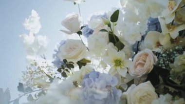  Close-up of wedding arch decorated with flowers in white and blue colors, roses, chrysanthemums and hydrangeas, blue sky on the background slow motion, outside wedding ceremony. 4k footage