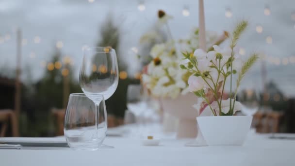 小さな居心地の良い結婚式パーティーで背景にパステル野生の新鮮な花 ドリンクやレトロなランプのためのメガネ スローモーションでクローズアップ結婚テーブルの設定 高品質4K映像 — ストック動画
