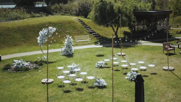 婚礼拱形装饰的顶部 白色和蓝色的花朵装饰着白色的椅子和小灯泡灯慢动作 婚外仪式 高质量的4K镜头 — 图库视频影像