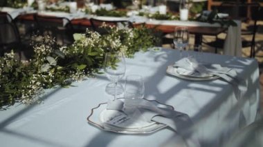 Bride and groom place settings at wedding reception table, beautiful plates with a gold border on a delicate blue tablecloth shadows on the table slow motion. High quality 4k footage