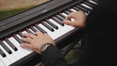 Close-up hands of young man playing electric piano on outdoor party. Man in black suit playing piano. Playing music instrument, slow motion. High quality 4k footage