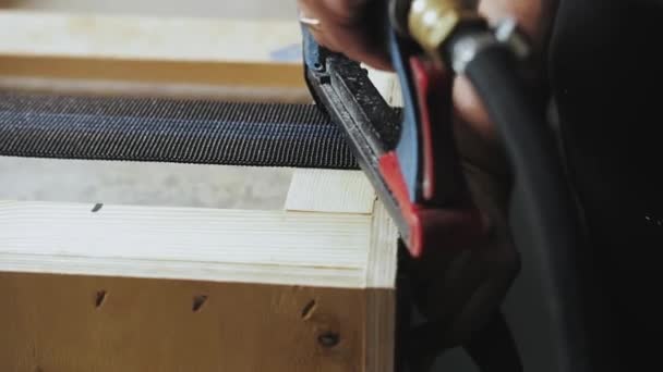 工人们的密切合作在一家家具厂做沙发 木匠用气动订书机把织物固定在木制框架上 在沙发上做一个小手的男人 慢镜头 — 图库视频影像