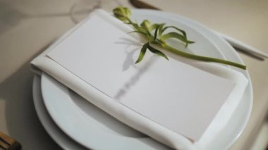 Güzel bir düğün dekoru, hepsi beyaz, yeşil renkli. Klasik servis tabakları ve masada altın çatallar. El kamerası, ağır çekim. Yüksek kalite 4k görüntü