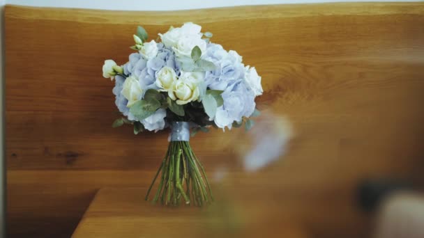 白いバラと青いリボンの青いアジサイの花嫁の花束は 木製のスタンド 結婚式のアクセサリー ソフトブラー スローモーションハンドヘルドショットに立っています 高品質4K映像 — ストック動画