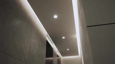 Minimalist iç mekanlı yuvarlak modern tavan lambası ve gizli LED arka lambası. Işıklandırma ekipmanlarıyla minimal iç mekan. Modern lamba. Şatafatlı Avize, yavaş çekim.