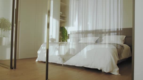 オープンガラスのドアで寝室の入り口のドリーショットは ベージュの寝具 スローモーションでベッドの上に太陽を光線 高品質4K映像 — ストック動画
