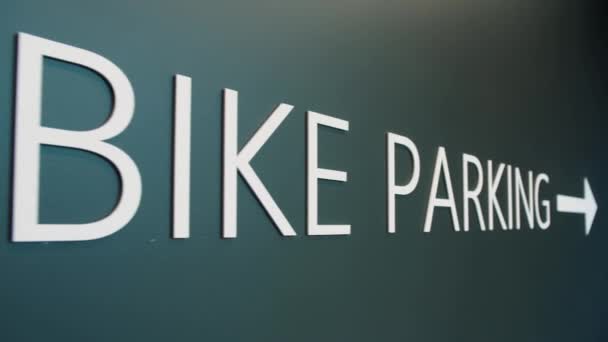 閉じる 建物内の碑文自転車駐車場まで 緑の色の背景に自転車の駐車標識 スローモーションドリーショット 高品質4K映像 — ストック動画