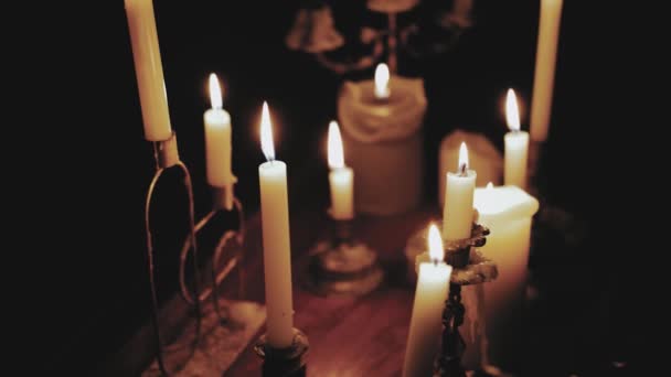 许多人在黑暗的房间里的木制桌子上燃着蜡烛 只有蜡烛才能点亮 钢琴上燃着蜡烛 动作缓慢 高质量的4K镜头 — 图库视频影像