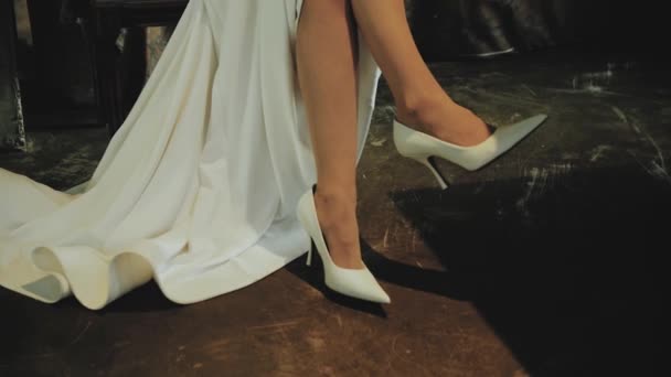 Gelinin Uzun Beyaz Gelinliği Yüksek Topuklu Ayakkabıları Sandalyede Oturuyor Kadın — Stok video