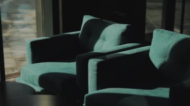 Koyu turkuaz koltuklarda gölgeler, binanın girişindeki pencerenin yanında iki sandalye, ağır çekimde çekimler. Yüksek kalite 4k görüntü