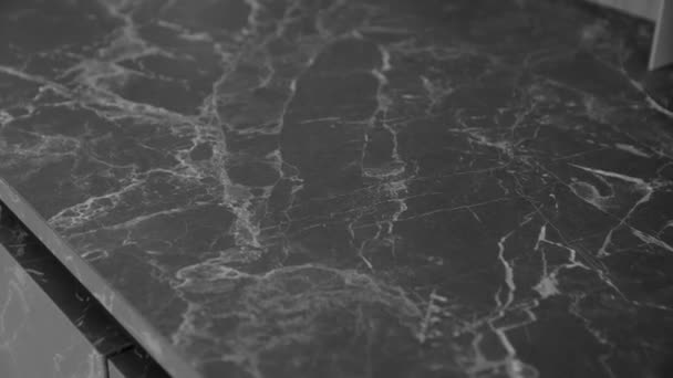 閉じる美しい花崗岩の黒と灰色のカウンターの上のショットを カメラの動きが遅い移動します 花崗岩の石で作られたカウンタートップ付きのキッチンデザイン テクスチャと背景 高品質4K映像 — ストック動画