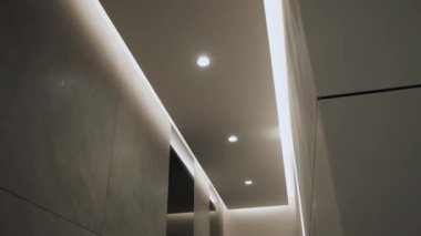 Minimalist iç mekanlı yuvarlak modern tavan lambası ve gizli LED arka lambası. Işıklandırma ekipmanlarıyla minimal iç mekan. Modern lamba. Şatafatlı Avize, yavaş çekim.
