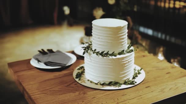 レストランの白い花で装飾された結婚式のアーチの近くの木のテーブルの緑の泉で飾られた美しい結婚式のケーキのクローズアップ ゆっくり動き 高品質の4K映像 — ストック動画