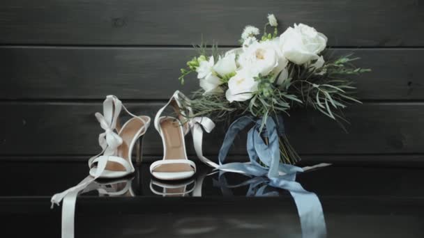 ブライダルシューズと素朴なスタイルの結婚式で装飾されたテーブル上のバラと緑の美しい花束の構成 花嫁のための美しい花束 遅い動きのショット 高品質の4K映像 — ストック動画