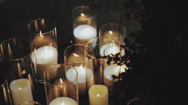 장식된 결혼식 테이블 꽃병에 양초를 태우는 양초는 어두운 배경을 태웁니다 — 비디오
