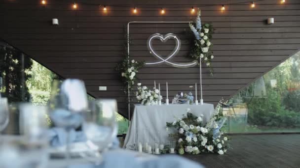 stock video Beautiful wedding table decor, all decorated in pastel white colors. Festive served with bouquet with fresh flowers, plates, glasses on the table, camera moving slow motion. High quality 4k footage