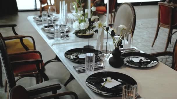 美しい結婚式の装飾 すべての黒と白の色で飾られました お祝いの装飾されたテーブルのドリーショット それに柔らかい花と美しい黒のプレート キャンドル テーブルの上のワイングラス 4Kの映像 — ストック動画