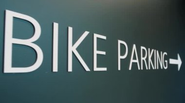 Binanın içine parkeden yazıtları yakın çekim bisikleti. Yeşil arka planda bisiklet park yeri tabelası, yavaş çekim. Yüksek kalite 4k görüntü
