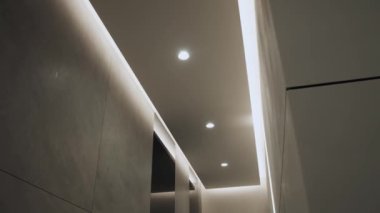 Minimalist iç mekanlı yuvarlak modern tavan lambası ve gizli LED arka lambası. Işıklandırma ekipmanlarıyla minimal iç mekan. Modern lamba. Şatafatlı Avize, yavaş çekim.