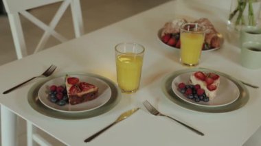 Sağlıklı kahvaltı cheesecake ile yabanmersini ve ahududu güzel servis edilir beyaz masa üzerinde portakal suyu ile birlikte. Evde kahvaltı, insan yok, ağır çekim. Yüksek kalite 4k görüntü