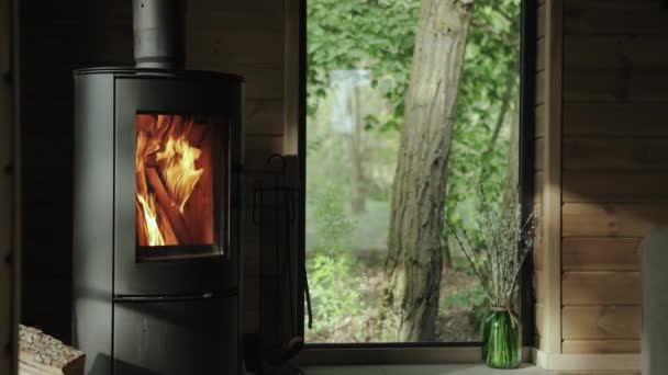 特写镜头舒适的房子炉火把火堆在一间小房子里 木墙在背景上 美丽的窗户在夏天看到绿色的森林 动作缓慢 高质量的4K镜头 — 图库视频影像