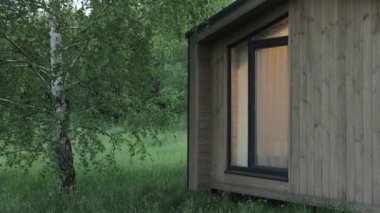 Kapalı ahşap İskandinav evi pencerenin ışığı yanıyor, ormanın ortasında sessiz bir orman kulübesi, evin yakınında yapayalnız huş ağacı. Turist evi, av evi, ahşap bina. 4k