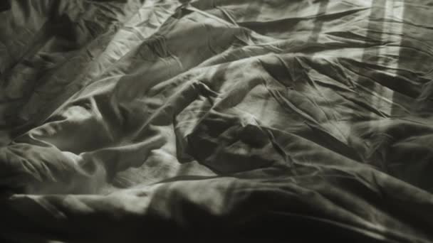 清晨的特写镜头 凌乱的床 阳光和阴影在折叠床上 床上用品特写灰色薄片慢动作 是的高质量的4K镜头 — 图库视频影像
