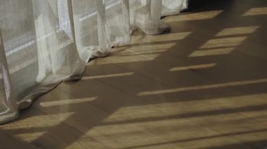 Close-up sunlight shadows from the window on the wooden floor, the tulle touches the floor, slow motion shot, textures, backgrounds. High quality 4k footage