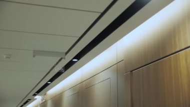 Modern hidden ceiling lamps in minimalist hall interior, hidden LED backlight. Minimalist Interior with lighting equipment. Contemporary modern lamp. Luxury Chandelier, slow motion dolly shot. 4k 